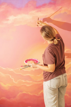 a woman paints a picture on a wall, wall painting at home or in a workshop, interior design with an artistic patternの写真素材