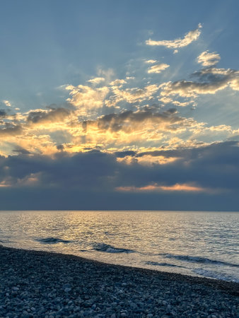 The Serene Sunset Casts Its Colors Over the Tranquil Ocean Waves, Creating a Beautiful Sceneの写真素材