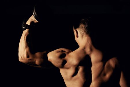 Bodybuilder with dumbbells on a dark background.の写真素材