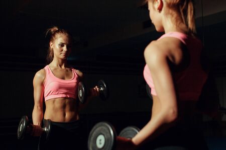 young woman in the gym, exercise for the bicepsの写真素材