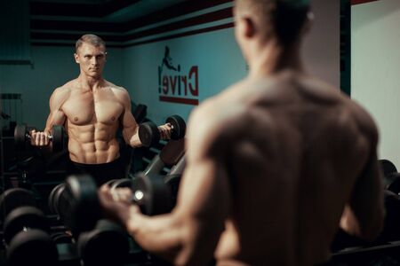 Young bodybuilder man doing exercise dumbbellの写真素材