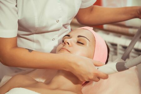 Hardware cosmetology. Closeup picture of lovely young woman getting lifting procedure in a beauty parlour.の写真素材
