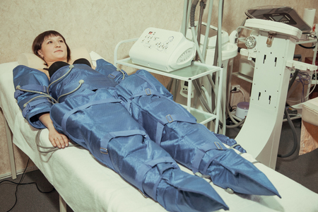 Pressotherapy machine on woman in beauty center. Cosmetic medicine devicesの写真素材