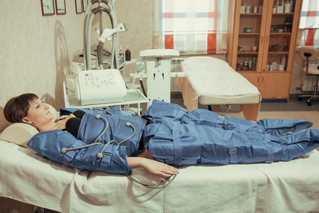 Doctor checking legs pressotherapy machine on woman patient in hospital bedの写真素材