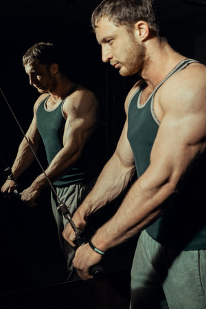 Young athletic athlete doing exercises on the press, biceps in the gym. Bodybuilderの写真素材