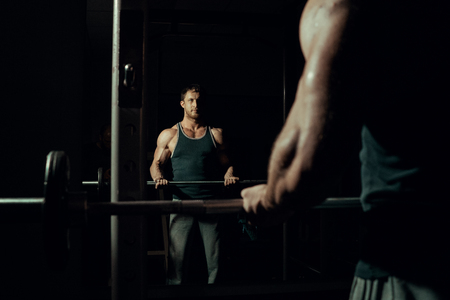 Young handsome man with big biceps lifts a barbell in the gym. Bodybuilderの写真素材