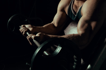 Hands of an athlete close-up, which does an exercise with a barbell. gym. biceps