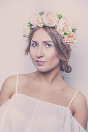 Beautiful girl with vintage flowers on her head on a white background close-up.の写真素材