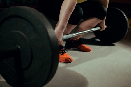 Strong woman doing sit-ups with a barbell in the gymの写真素材