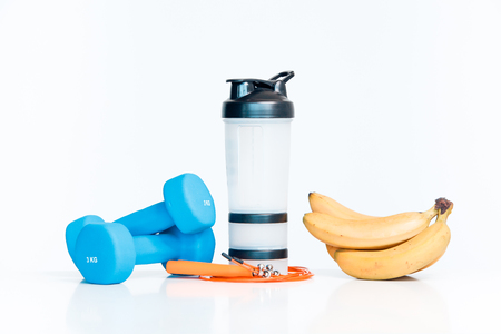 The concept of a healthy diet. Small dumbbells. Shaker. Bananas. Measuring tape waist. The skipping rope. on a white background. healthy lifestyle. sport. Fitness food.の写真素材