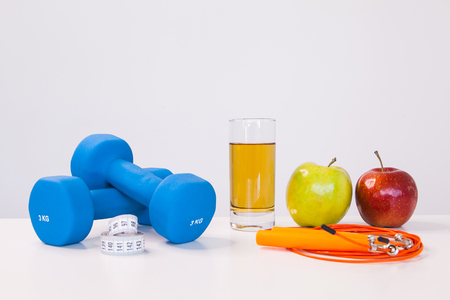 The concept of a healthy diet. Small dumbbells. Apple juice. The skipping rope. Green apple. Red Apple. on a white background. healthy lifestyle. sport. Fitness food.の写真素材