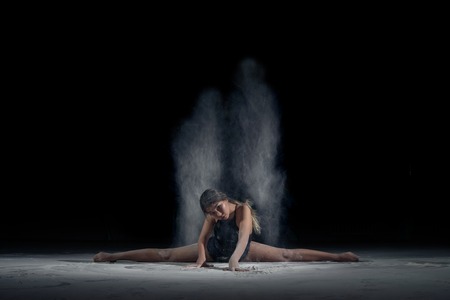 Girl dancing in the flour on the black backgroundの写真素材