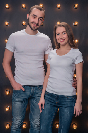 A girl and a boy model posing in white shirts and blue jeans in the studioの写真素材