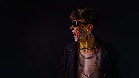 A guy with a tiger on his face wearing sunglasses on a dark backgroundの写真素材
