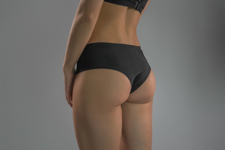 A sporty ass girl on a gray background. Sports figure