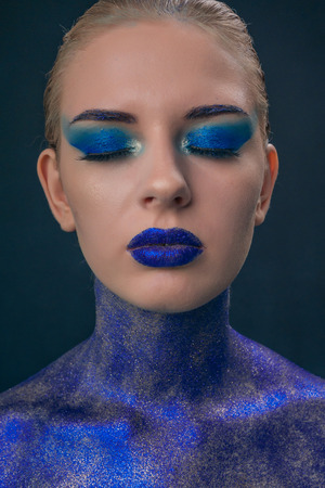 Portrait of a girl strewn with blue sequins with bright make-upの写真素材
