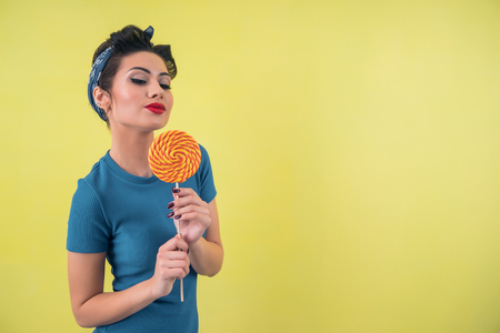 Portrait of a sexy retro girl with a lollipop on a bright yellow backgroundの写真素材