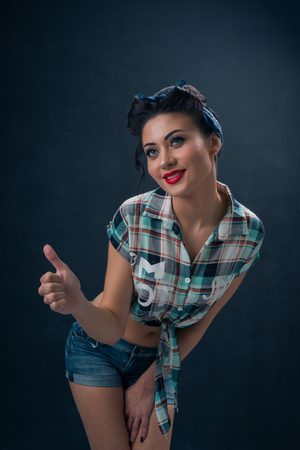 Sexy young beautiful girl in pin-up style smiling on a dark backgroundの写真素材