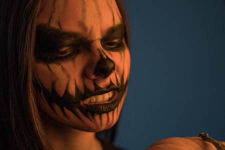 Close-up portrait of a girl with a terrible dead man mask on a dark background. Halloween Holidayの写真素材