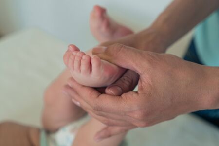Close-up of a woman's hand holding a child's leg. Baby massage.の写真素材