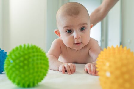 Funny little baby playing with rubber balls. The child learns the worldの写真素材