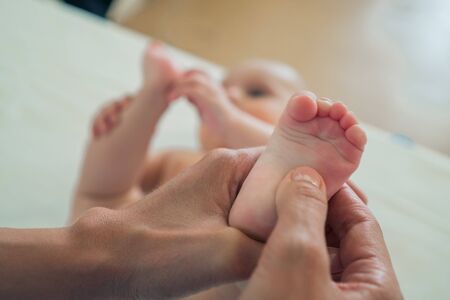 Small feet of the baby in the womens hands. The concept of motherhood, care and warmthの写真素材