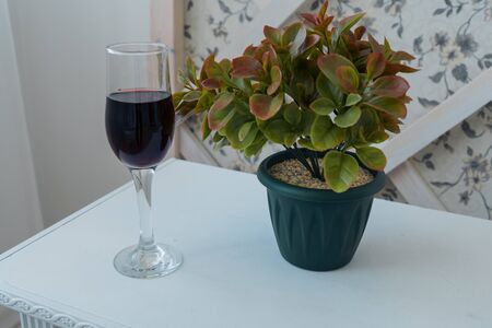 A glass of wine and a homemade flower on a table near the wall. Home design. Backgroundの写真素材