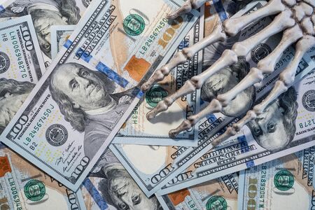 Skeleton hand lying on the dollars.の写真素材
