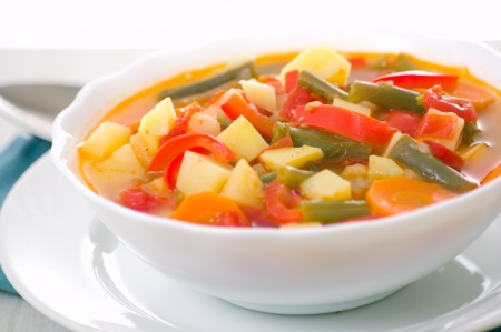 Fresh vegetable soup made of green bean, carrot, potato, red bell pepper, tomato in bowlの写真素材