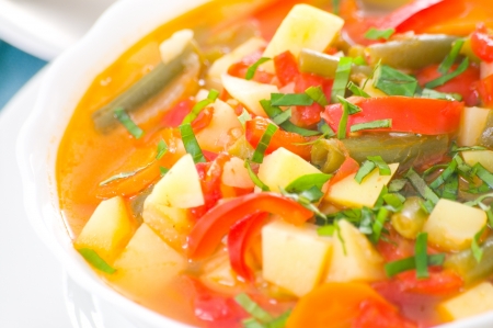 Fresh vegetable soup made of green bean, carrot, potato, red bell pepper, tomato in bowlの写真素材