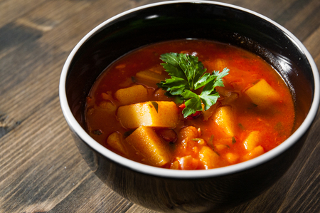 Bean and vegetables soup in ceramic bowl on wooden tableの写真素材