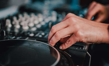 DJ Hands creating and regulating music on dj console mixer in concert nightclub stage