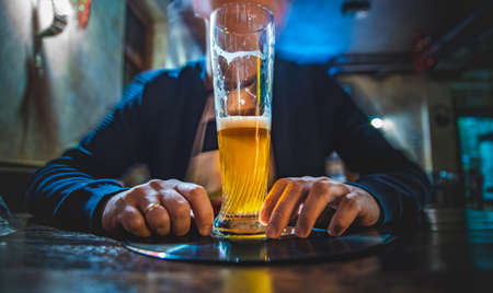man holds a glass of beer in his hand at the bar or pubの写真素材