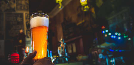 man holds a glass of beer in his hand at the bar or pubの写真素材