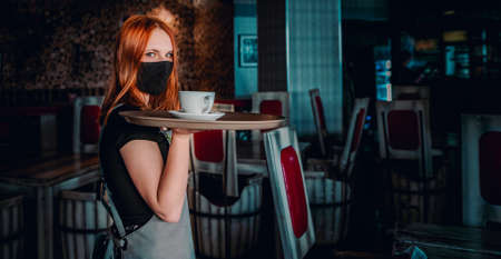 Portrait young waitress standing in cafe. girl the waiter holds in bunches a tray with utensils. Restaurant serviceの写真素材