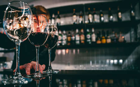 bartender pouring red wine into a glass in cafe or bar
