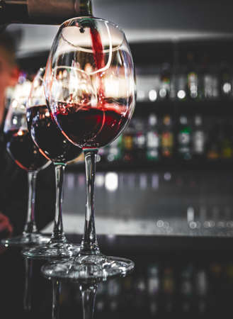 bartender pouring red wine into a glass in cafe or barの写真素材