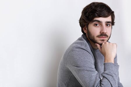 Sideways portrait of young hipster having dark beard with moustache big dark eyes, thick eyebrows...
