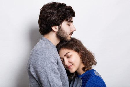 Young couple in love. A pretty young girl snuggling up to her bearded boyfriend. Sincere love between hipsters. Couple supporting each other and relying on each other having nice time togetherの写真素材
