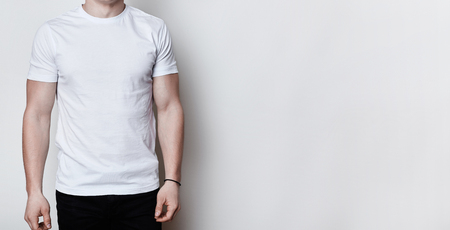 A portrait of a man having athletic body wearing blank white t-shirt standing on white background with copy space for your advertisment. Clothes advertising.T-shirt design and people concept.の写真素材