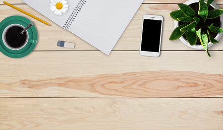 Minimal working home desk of creative person. Home stuff of blank notepad, pencil, rubber, mug of coffee, smartphone and pot of flower. Creative design mockup set of workspace desk with suppliesの写真素材