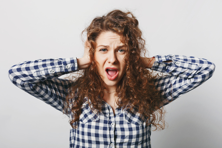 Negative emotions and people. Desperate female keeps hands on ears, ignores someone, opens mouth widely, screams with hopelesness, feels anxiety and frustration, isolated over white backgroundの写真素材