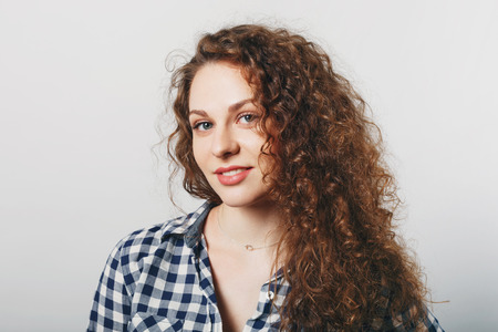 Horizontal portrait of delighted pleasant looking young female with curly hair, blue eyes and...