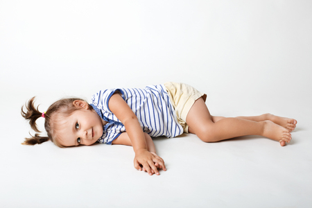 Funny small female child, wears casual t shirt and shorts, has two pony tails, looks joyfully directly into camera, isolated over white studio background. Childhood, positivity and happiness conceptの写真素材
