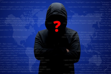 Mysterious unknown hacker in black clothing with hoodie, stands crossed hands against dark digital...