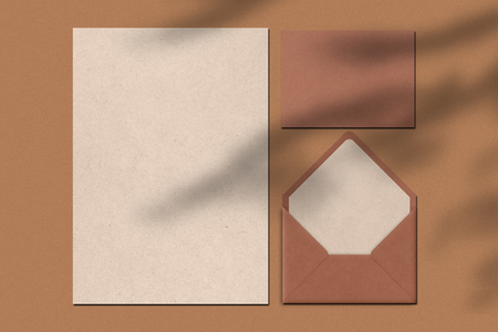 Blank sheet of paper and letter against brown background. Envelope. Writing notes concept. Top view. Horiontal shot. Empty space for your information.の写真素材