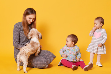A delighted happy mom plays with her favourite pet, sitting on the floor, looking at it. Surprised...