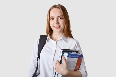 Close up portrait of young girl teenager carries rucksack, holds colorful folder with papers.の写真素材