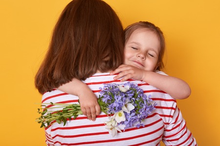 Happy Mother's day! Child daughter congratulates mom and gives her flowers. Mum and little girl...