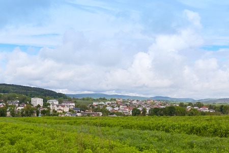 Image of best place of world, village in mountains, photo of nature scenary, blue sky with clouds, green grass and many houses on bottom of hills, sunny summer day, wonderful landscape.の写真素材